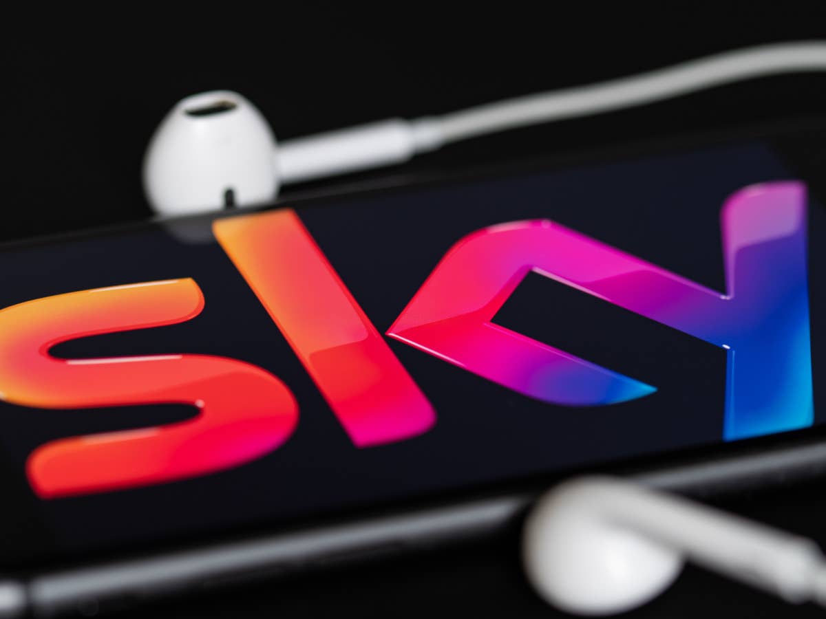 Sky Logo auf einem Smartphone neben Kopfhörern.