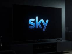 Logo von Sky auf einem Fernseher in einem dunklen Wohnzimmer.