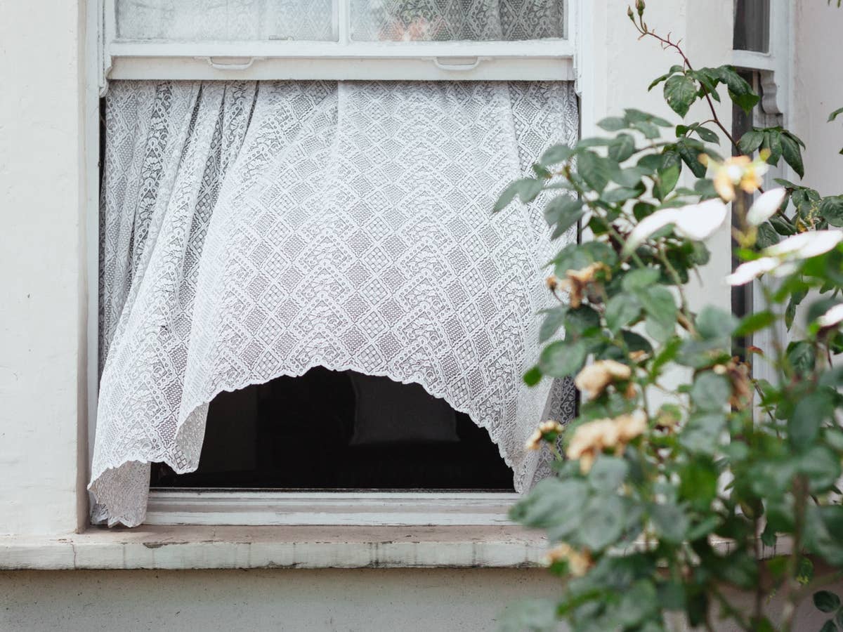 Ein offenes Fenster, aus dem eine Gardine weht