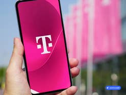 Smartphone auf dem das Telekom-Logo zu sehen ist, im Hintergrund ein Telekom-Gebäude, KI-generiert