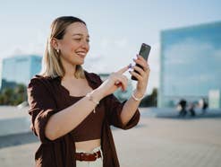 Eine Frau schaut auf ihr Smartphone und lacht