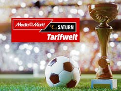 Ein Fußball und ein Pokal im Vordergrund, dahinter ein Rasen und ein gefülltes Stadion Darauf das MediaMarkt/Saturn-Logo der Tarifwelt.