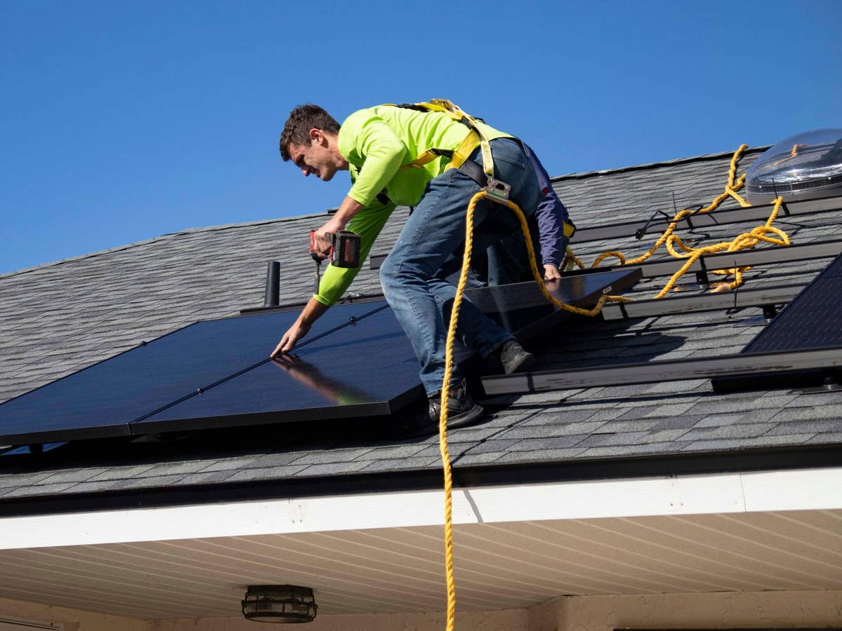 Ein Handwerker montiert eine Solaranlage auf einem Dach