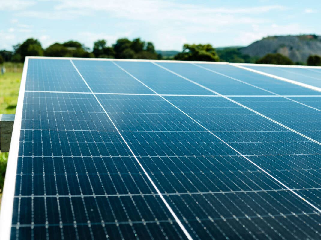 Solarmodul vor Wiese, Bergen und Bäumen