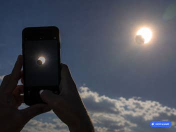 Ein Handy fotografiert die Sonnenfinsternis.