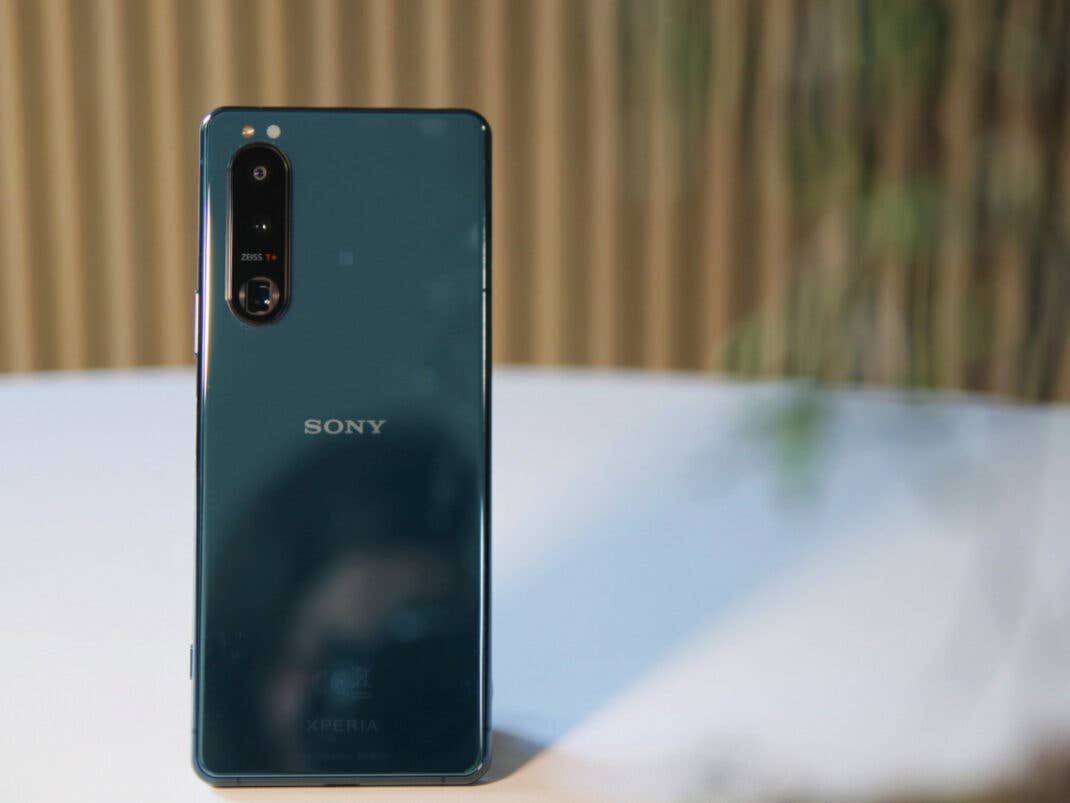 Die Rückseite des Sony Xperia 5 III mit Spiegelung, vor einer Holzwand auf einem weißen Tisch.