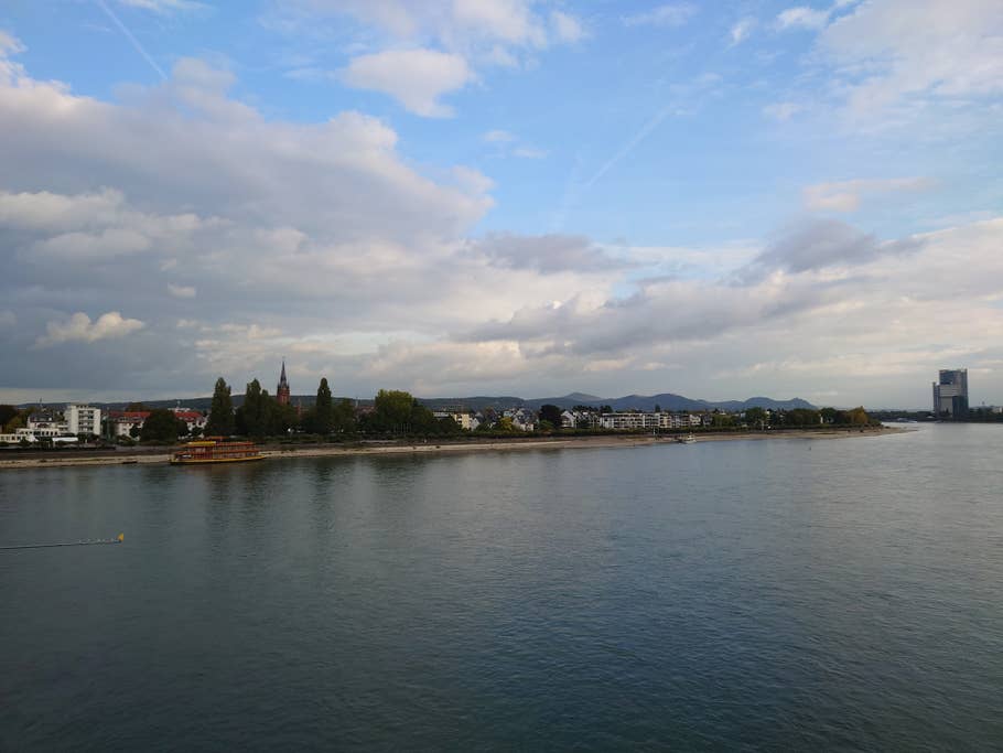 Der Rhein am frühen Abend, mit blauem Himmel und Wölkchen und dem Stadtufer.
