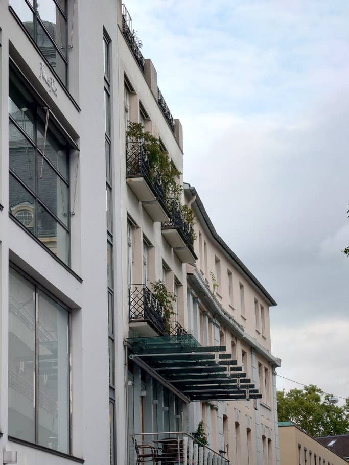 Ein Stadtzentrum mit Häuserfassaden, an einen Balkon herangezoomt.