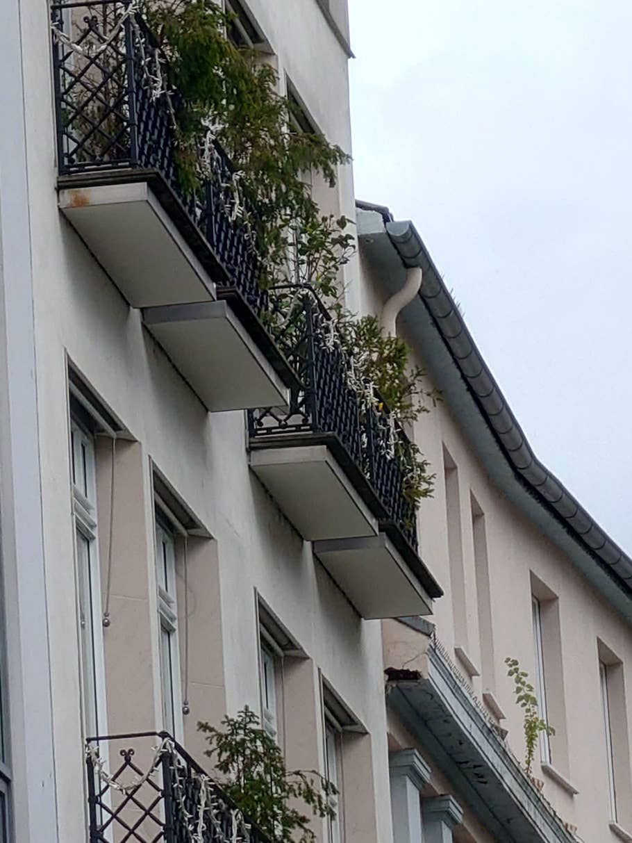 Ein Stadtzentrum mit Häuserfassaden, an einen Balkon herangezoomt.