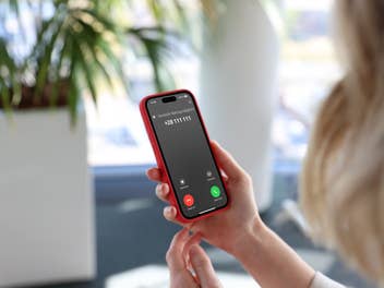 Ein Smartphone mit einer Telefonnummer, bei der vor Betrug gewarnt wird