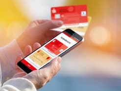 Die Sparkassen-App zum mobilen Bezahlen auf einem Handy, daneben zwei Sparkassen-Karten.
