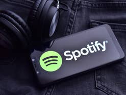 Spotify-Logo auf einem Smartphone neben einem Kopfhörer.