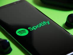 Spotify-Logo auf einem Smartphone neben Kopfhörern.