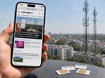 Ein Handy mit inside digital Webseite vor einem Stadthintergrund, im Vordergrund Spusu-SIM-Karten