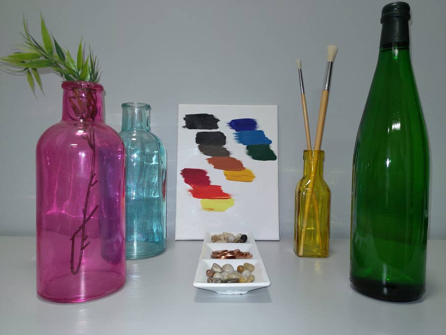 Tisch mit Flaschen, Farben auf einer Leinwand und Münzen in einer Schale