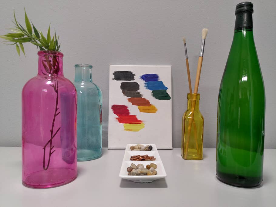 Tisch mit Flaschen, Farben auf einer Leinwand und Münzen in einer Schale
