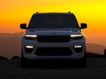 Front eines Jeep mit Sonnenaufgang im HIntergrund.