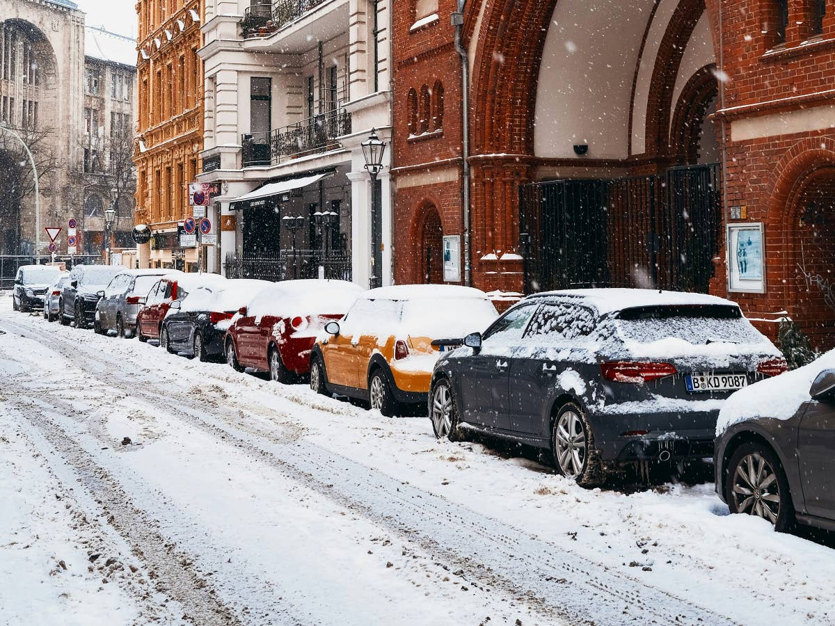 Straße mit geparkten Autos von Schnee bedeckt