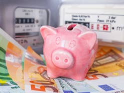 Sparschwein steht auf Geldnoten vor einem Gaszähler und einem Stromzähler