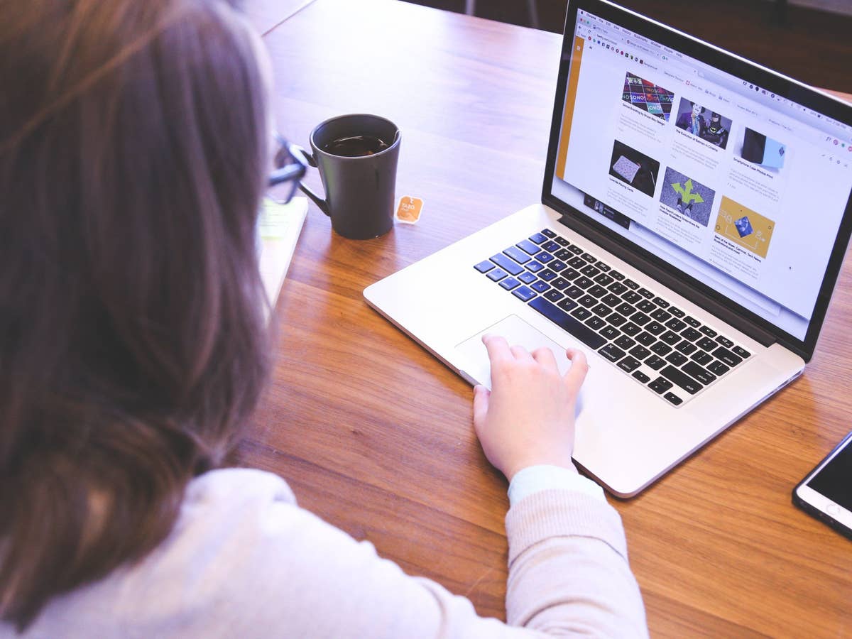 Eine Frau sitzt am Tisch an einem Laptop