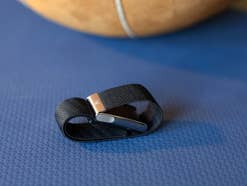 Ein Whoop MG Sensorarmband liegt auf einer blauen Oberfläche, mit einem Basketball, der teilweise im Hintergrund sichtbar ist.