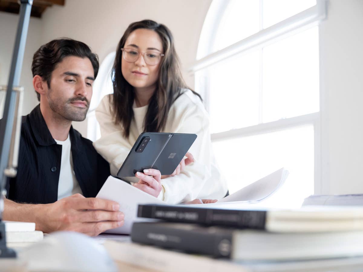 Ein Mann zeigt einer Frau etwas auf dem Microsoft Surface Duo 2 Smartphone