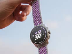 Suunto Race 3S wird von einer Frau am Armband baumelnd gehalten.