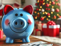 Sparschwein steht in einem Wohnzimmer mit weihnachtlicher Umgebung.