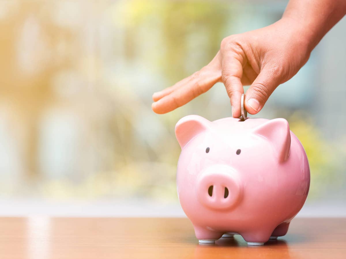 Tagesgeld-Kracher: Erste deutsche Bank knackt neuen Topwert Hand wirft Münze in ein Sparschwein.