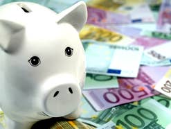 Sparschwein steht auf und neben Euro-Geldscheinen.