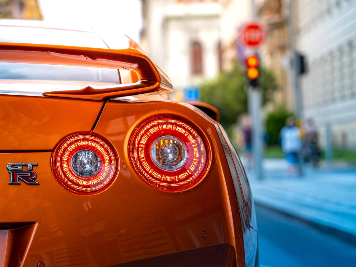 Täuschung im Verkehr: Verbrenner-Fake für das E-Auto Rücklichter eines sportlichen Autos von Nissan, das an einer Ampel steht.