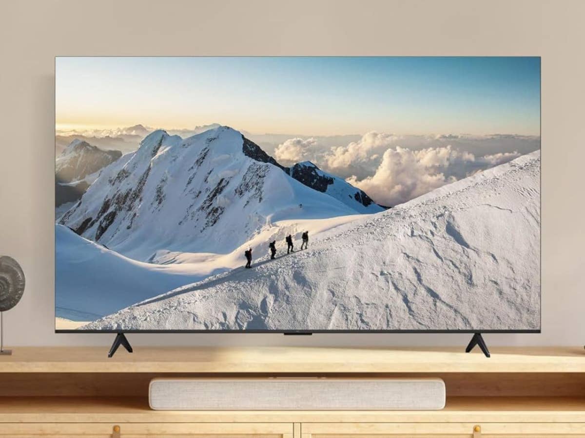 TCL-Fernseher im Angebot TCL Fernseher zeigt eine verschneite Gebirgslandschaft und steht in einem hellen Wohnzimmer