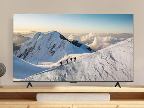 TCL Fernseher zeigt eine verschneite Gebirgslandschaft und steht in einem hellen Wohnzimmer