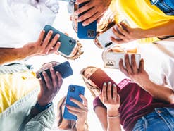Jugendliche nutzen Smartphones in einem Kreis.