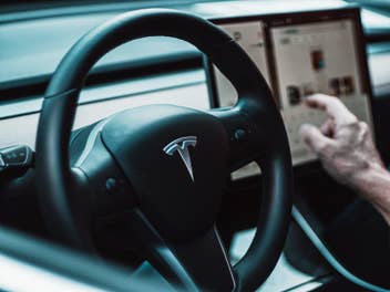 Ein Mensch sitzt am Steuer eines Teslas.