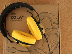 EIn gelbes Teufel ZOLA Gaming Headset liegt auf einem Karton.