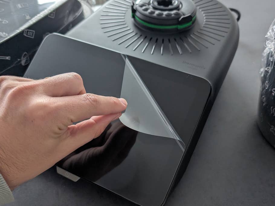 Eine Person zieht die Displayschutzfolie beim Thermomix ab