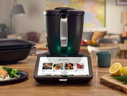 der Thermomix TM7 auf dem Küchentisch und mehreren Gerichten sowie Zubehör drum herum