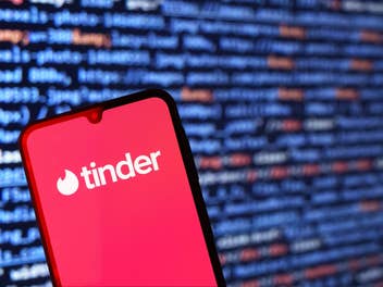 Tinder-App auf Smartphone und im Hintergrund laufen Zahlen.