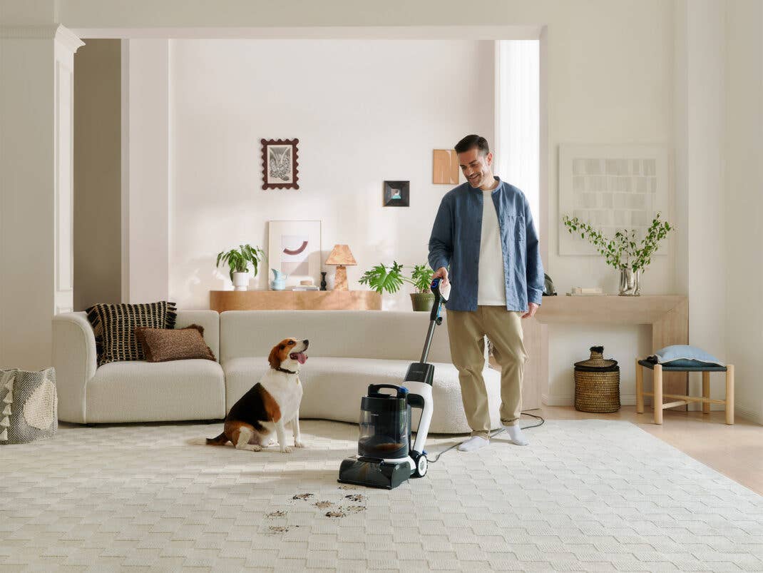 Eine Person nutzt einen Teppichreiniger um einen Teppich zu säubern.