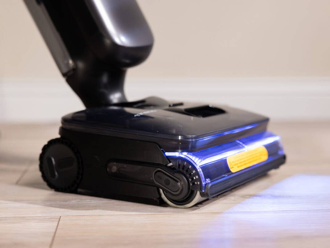 Die Bodendüse des Tineco Saugers beleuchtet mit einem bläulichen LED-Lichtkegel den Boden davor.
