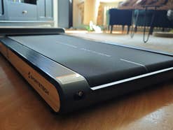 Woodpad Pro liegt im Wohnzimmer auf Boden, tiefe Perspektive von unten, man sieht Möbel, einen Teppcih