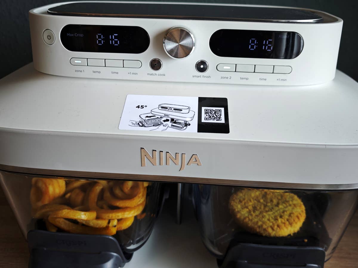 Die Ninja Crispi DualZone ist eine Heißluftfritteuse mit zwei seperaten Glasgarkörben und smarten Funktionen zum synchronisierten Heißluftfrittieren. Der Ninja Crispi DualZone frontal mit Pommes und Gemüsepattie in den Glasbehältern