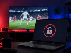 Ein Laptop mit einem Schloss-Symbol, im Hintergrund ein TV mit Fußball