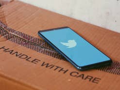 Ein Smartphone mit Twitter-Logo liegt auf einem Karton