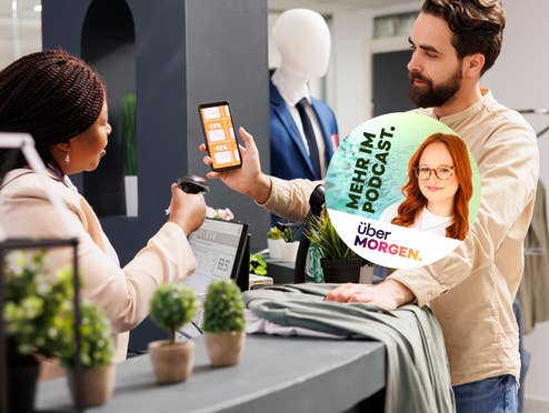 Ein weißer Mann zeigt einer schwarzen Verkäuferin sein Handy, auf denen Coupons angezeigt werden. Darüber liegt ein Button mit der Info „mehr im Podcast“.