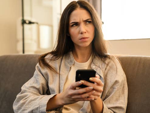 Überraschung: Zwei Mobilfunk-Discounter abgeschaltet Frau nutzt ein Smartphone mit zweifelndem Blick