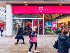 Mehrere Menschen laufen vor einer Telekom-Filiale hin und her.