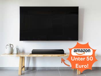 Ein Fernseher mit Soundbar auf einem Holz-Sideboard mit minimalistischer Dekoration