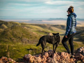 Frau mit Hund bei Wanderung in Bergen